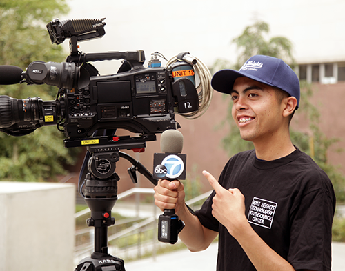Boyle Heights Tech YouthSource Center participant interning for ABC7 news, student pictured with a news camera and microphone