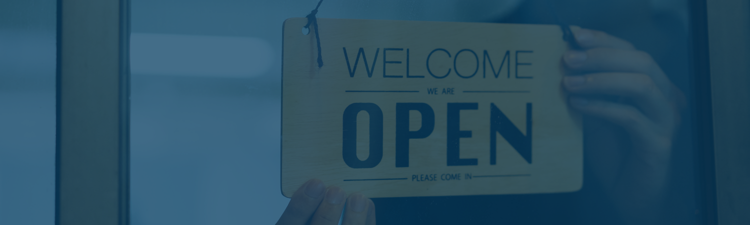 a yellow Welcome We Are Open sign with an opaque pale blue overlay